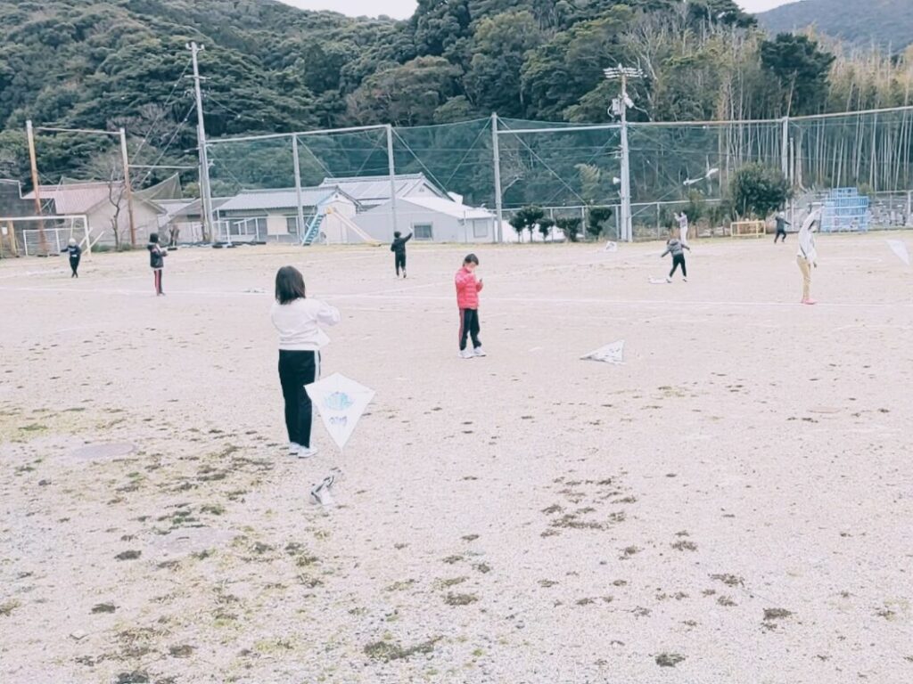 運動場で凧をあげる菅島小学校児童